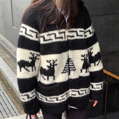 Person wearing a black and white patterned sweater with deer and tree design.