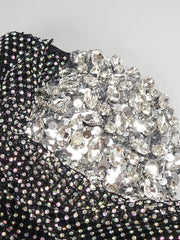 Close-up of a black garment with sparkling silver rhinestone embellishments on a light gray background.