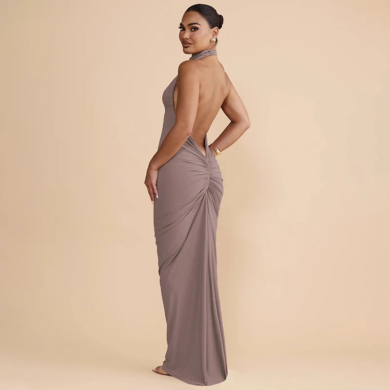 Woman wearing a long, elegant dress with a draped back on a beige background