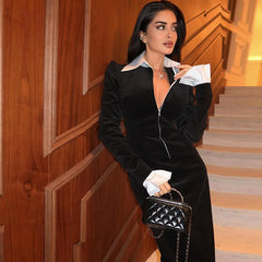 Woman in a black and white outfit holding a black handbag in an indoor setting.