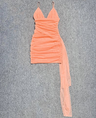 Peach-colored dress with a sheer side panel on a gray background