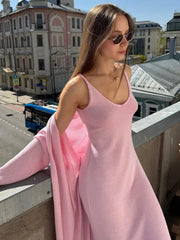Woman in a pink dress standing on a balcony with a cityscape background