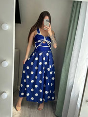 Woman wearing a navy blue polka dot tankini swimsuit with a white bow detail and matching skirt, posing for a mirror selfie.