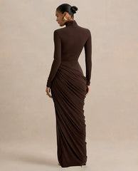 Woman wearing a brown long-sleeve gown with a draped skirt on a beige background