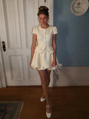 Woman in a white outfit standing in a room with a blue wall and white door.