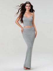 Woman wearing a gray sleeveless top and long skirt on a white background