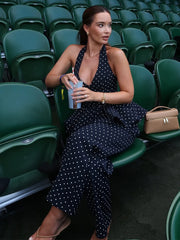 Woman in a polka dot dress sitting in a stadium with green seats.