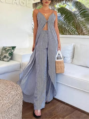 Woman in a blue and white striped dress standing in a tropical setting with palm trees.