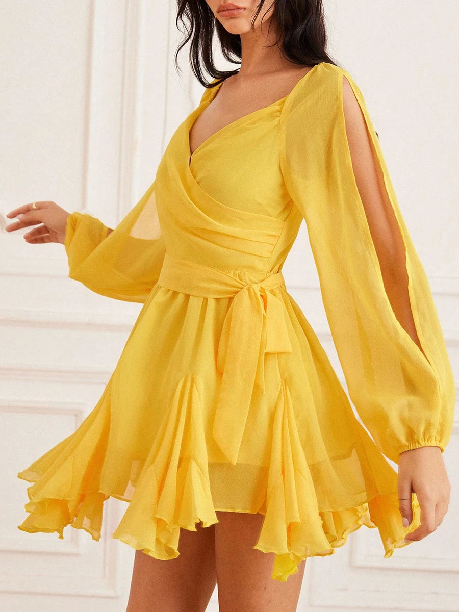Yellow dress with long sleeves and a tie waist on a white background