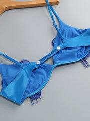 Blue bikini top on a gray surface with a wooden hanger.
