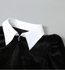 Black velvet garment with a white collar on a gray background