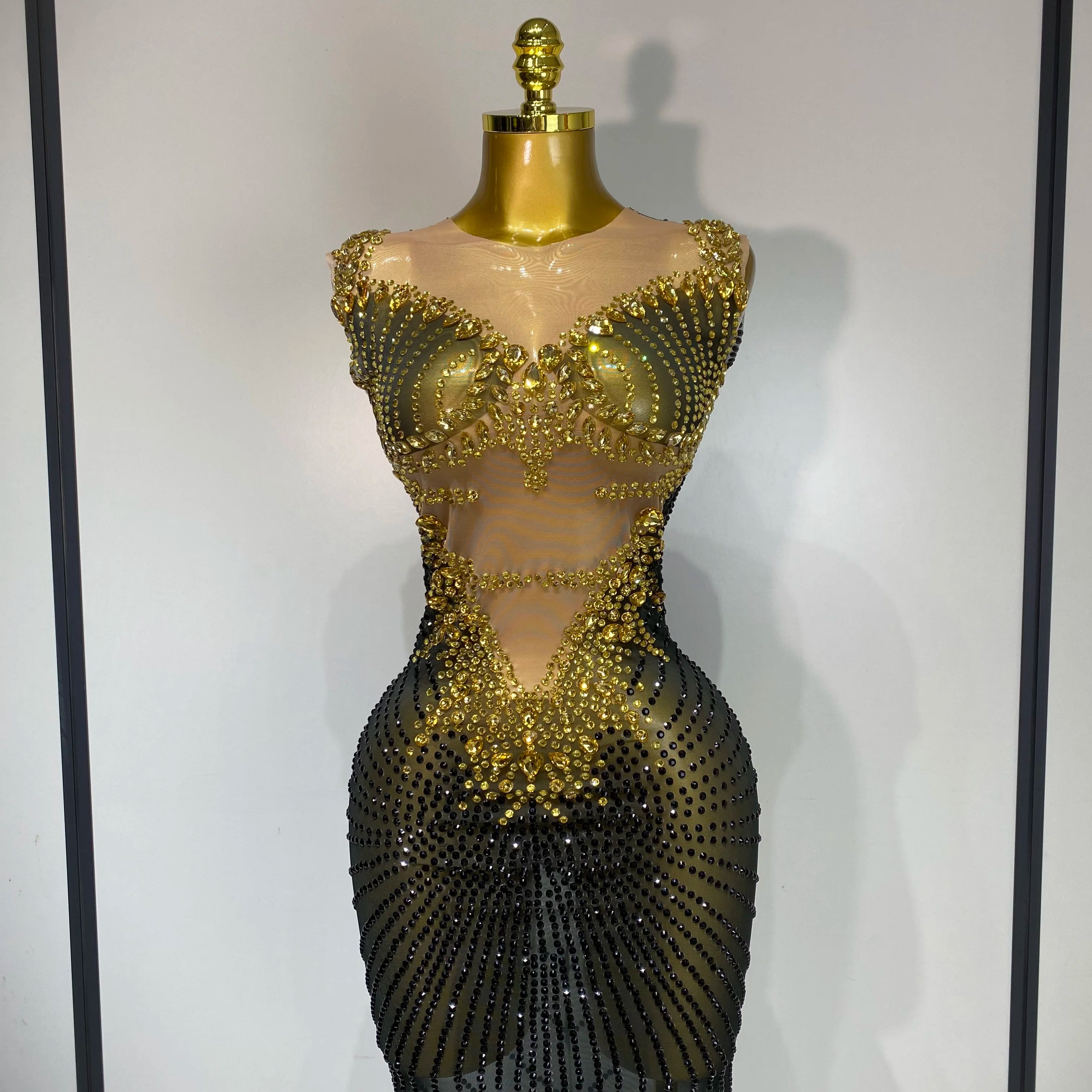 Gold and black beaded dress on a mannequin against a plain background