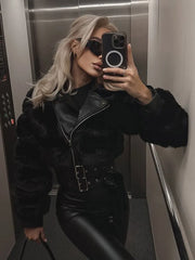 Person taking a mirror selfie wearing a black fur-lined jacket and black pants in an elevator.