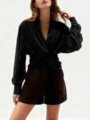 Woman wearing a black blouse and brown shorts on a white background