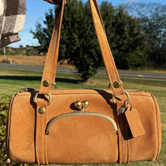 Brown leather handbag with gold accents in an outdoor setting