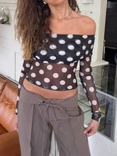 Woman wearing a polka dot top and brown pants in an indoor setting