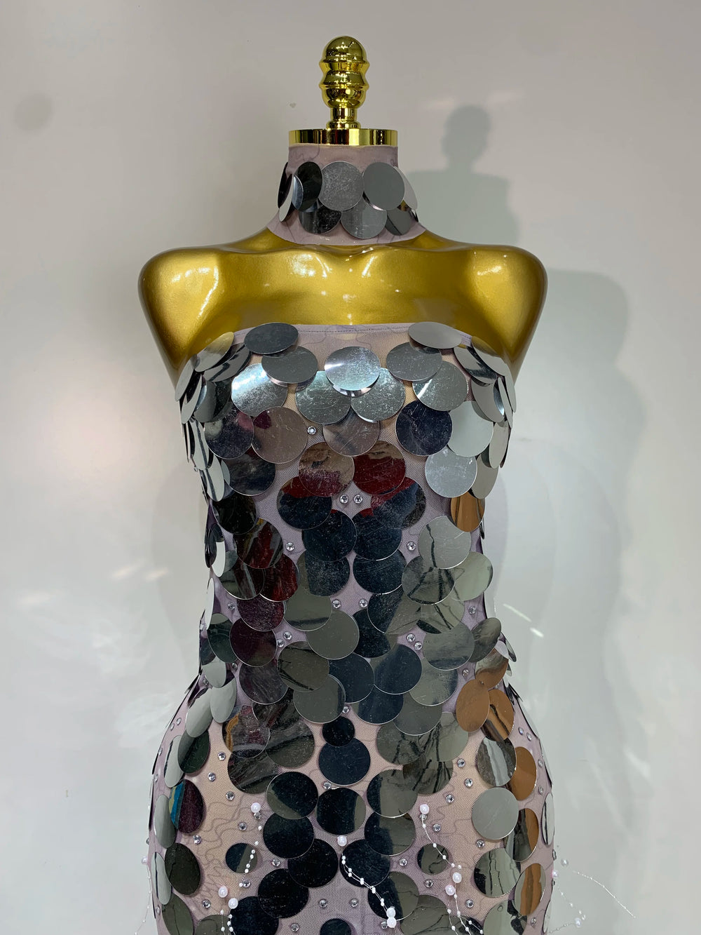 Mannequin wearing a dress with silver sequins on a white background