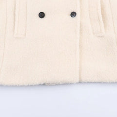Close-up of a cream-colored fabric with two black buttons on a light blue background