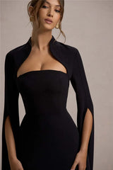 Woman wearing a black strapless dress with a matching jacket against a neutral background