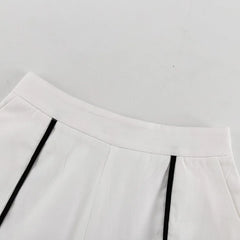Close-up of a white skirt with black pleats on a light gray background