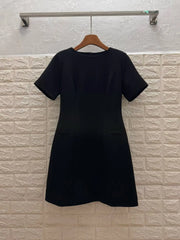 Black dress on a hanger against a textured white wall