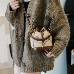 Person wearing a bear print bucket bag with brown faux leather trim.