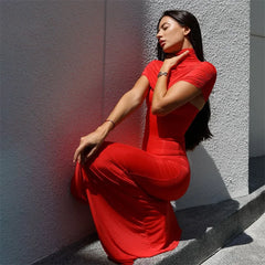 Woman in a red dress sitting against a textured wall.