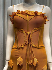 Mannequin wearing a mustard yellow dress with floral details on a gray background