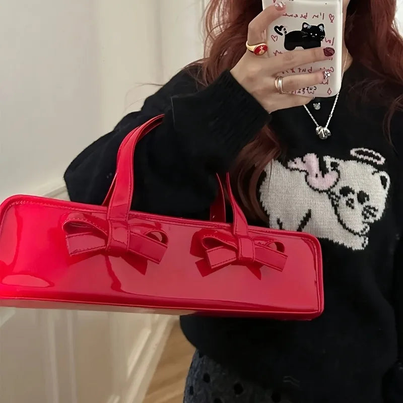 Close-up of a red patent leather baguette bag with bow detail
