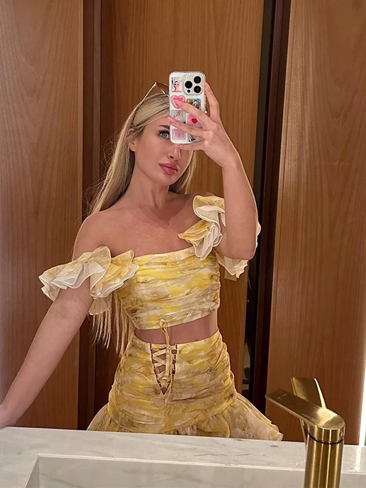 Woman taking a mirror selfie wearing a yellow off-shoulder outfit.