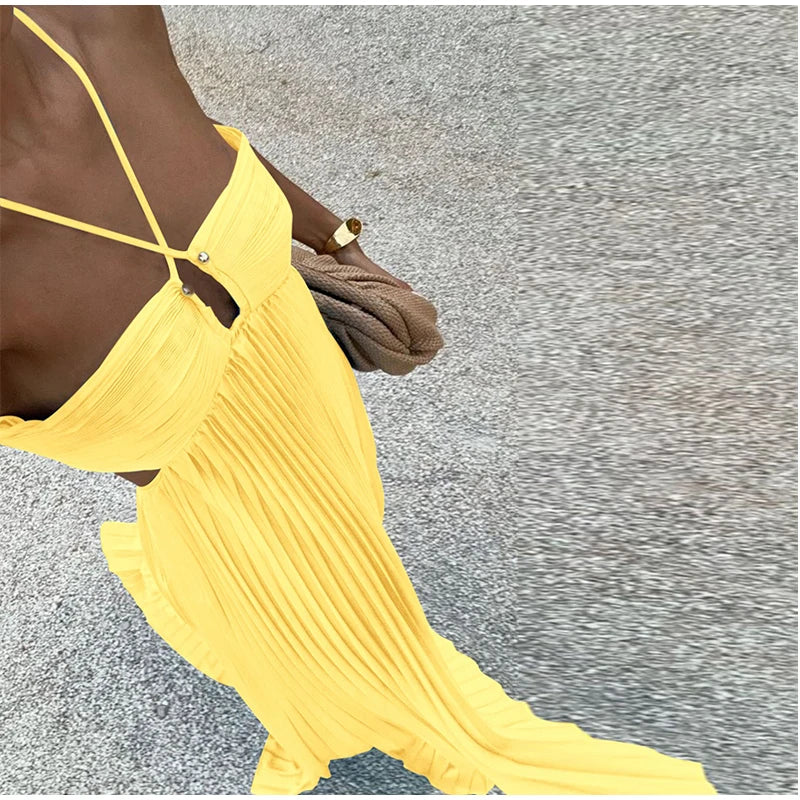 Person wearing a yellow dress with thin straps on a textured gray background