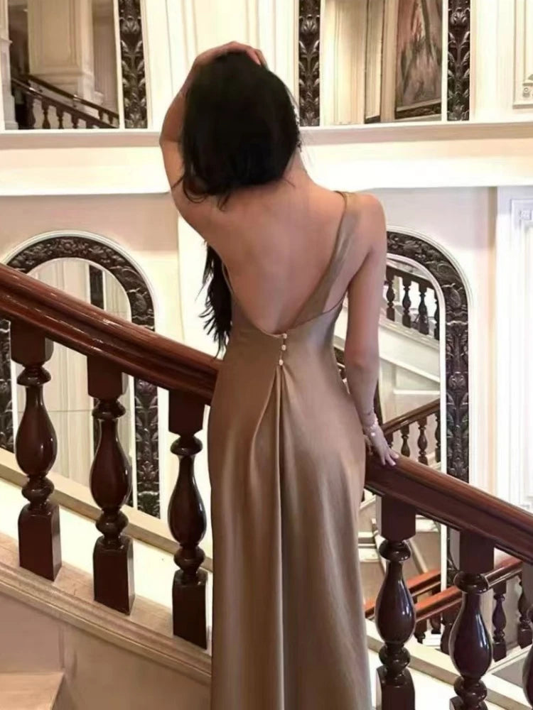 Woman on a staircase wearing a backless one-shoulder maxi dress