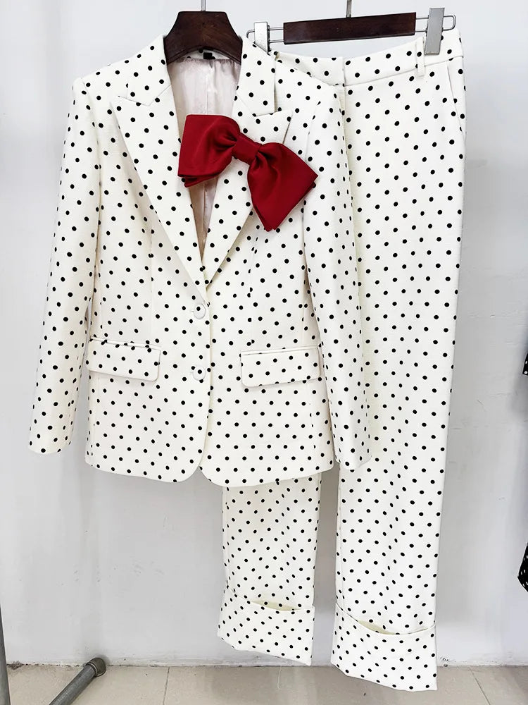 White polka dot print blazer and trousers with a red bow detail on a hanger.