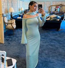Woman in a light green off-shoulder dress taking a mirror selfie in an ornate room.