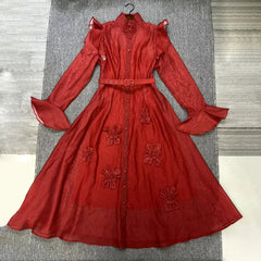 Red dress with floral embellishments on a gray surface