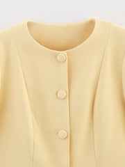 Close-up of a light yellow blouse with buttons on a light gray background