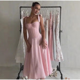 Woman wearing a pink dress standing in front of a rack with other dresses.