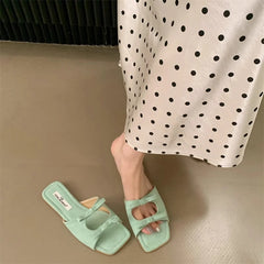 Green sandals worn with a polka dot dress on a beige floor.
