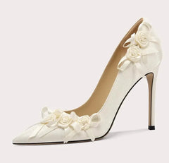 White high-heeled shoe with floral decorations on a light gray background