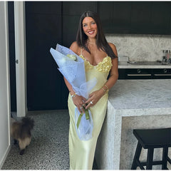 Woman in a yellow dress holding flowers in a kitchen