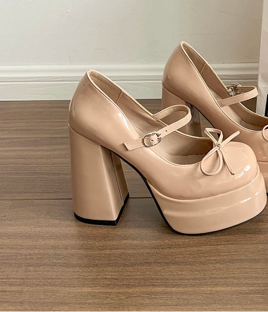 Beige platform shoes with block heels on a wooden floor.