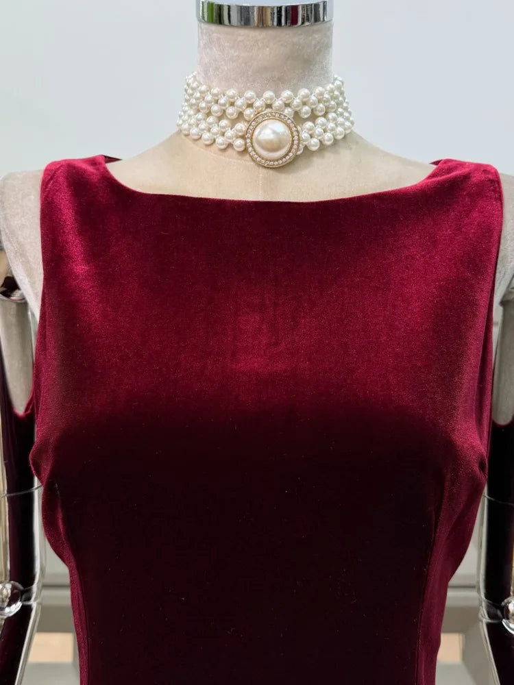 Mannequin wearing a burgundy top with a pearl necklace on a white background