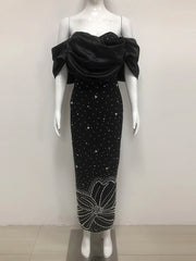 Black evening gown with floral embellishments on a mannequin against a white background
