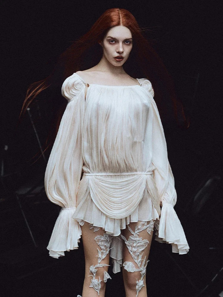 Woman wearing a white dress with floral lace details on a dark background