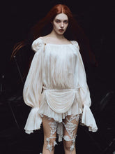 Woman wearing a white dress with floral lace details on a dark background