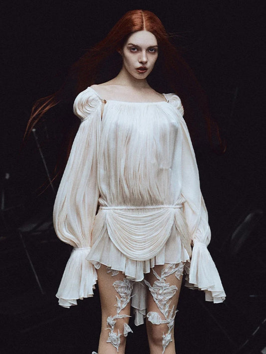 Woman wearing a white dress with floral lace details on a dark background