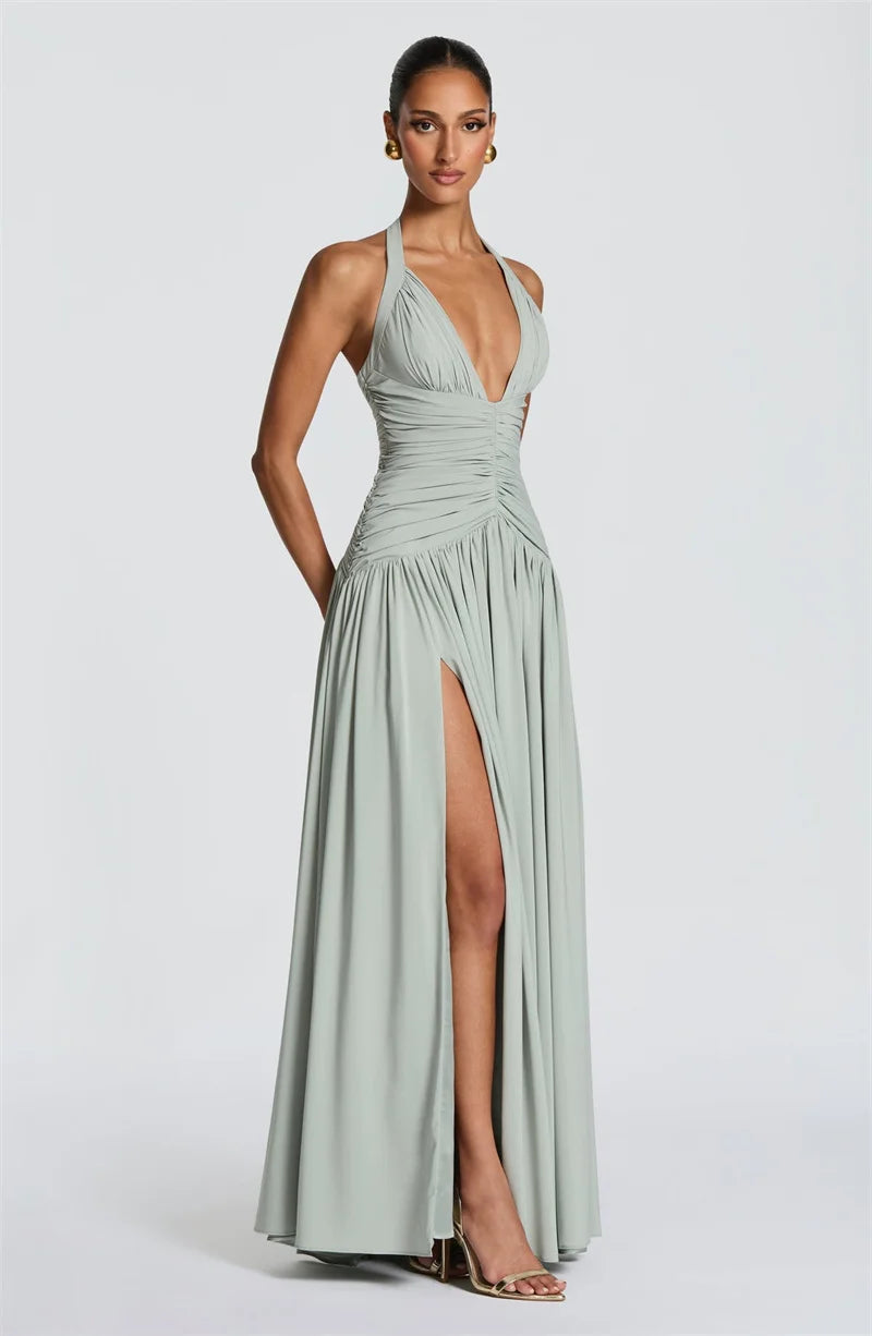 Woman wearing a light green halter neck gown with a high slit on a white background