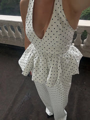 White polka dot dress with a deep neckline and ruffled details on a blurred background