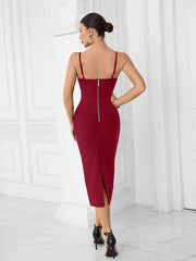 Woman wearing a red dress with thin straps and a back zipper, standing against a white paneled wall.