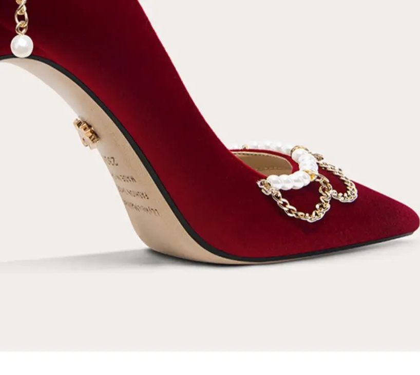 Red high-heeled shoe with gold chain detail on a white background